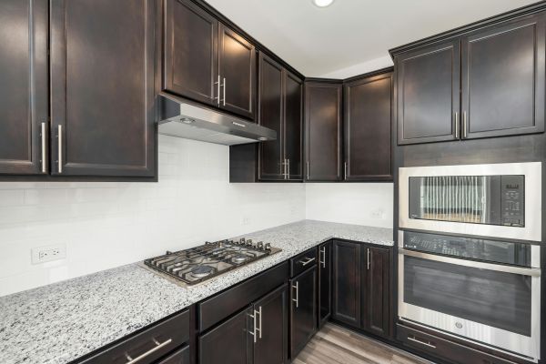 Elegant modern kitchen featuring dark wooden cabinets, sleek granite countertops, and built-in appliances.